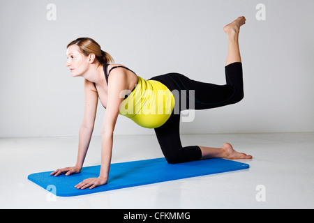 Pregnant woman exercising on mat to develop balance and muscular strength of the core trunk and leg muscles Stock Photo