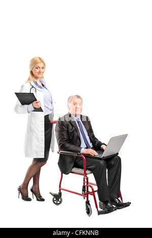 A nurse pushing a busy businessman working on a laptop in a wheelchair isolated on white background Stock Photo