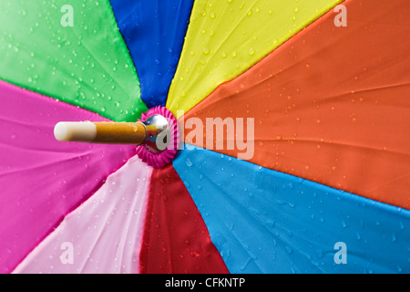 Close up of a multicoloured umbrella in the rain. Stock Photo