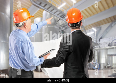 A team of construction workers with orange helmets at work place in a factory Stock Photo