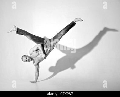 Young male dancer performing kick while doing a handstand. Shot in studio. Stock Photo