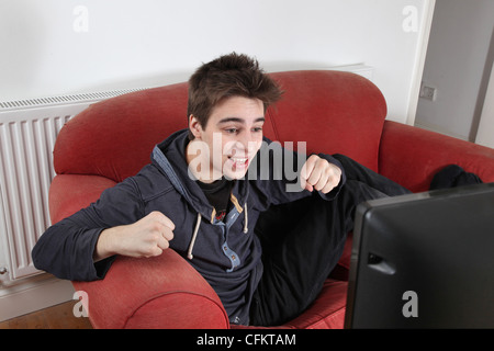 Enthusiastic young man watching tv alone. Stock Photo