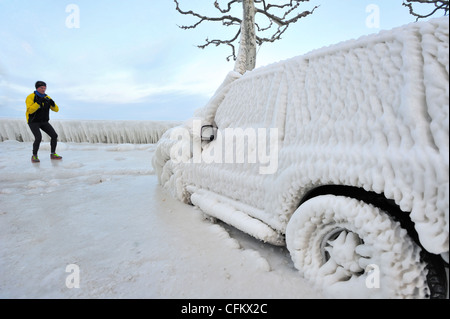 Man talking a photograph of a car frozen in ice in Versoix, Switzerland, by Lake Geneva Stock Photo