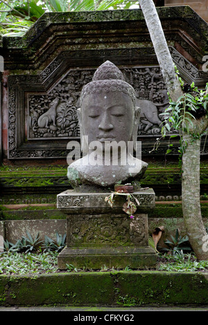 Indonesia Bali Ubud Buddha statue in lotus seat with hibiscus flowers ...