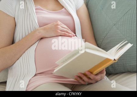 USA, New Jersey, Jersey City, Midsection of pregnant woman reading book Stock Photo