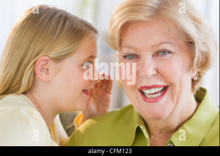 USA, New Jersey, Jersey City, Granddaughter (8-9) whispering to her grandmother ear Stock Photo