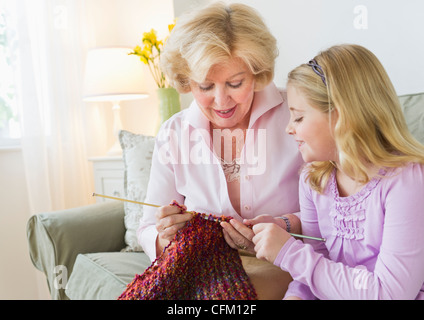 USA, New Jersey, Jersey City, Grandmother with granddaughter (8-9) knitting at sofa Stock Photo