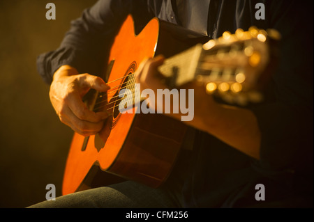 Close up of man playing acoustic guitar, studio shot Stock Photo