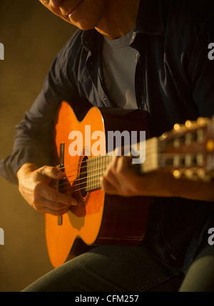 Close up of man playing acoustic guitar, studio shot Stock Photo