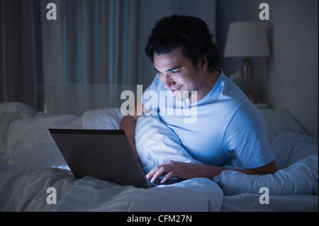 USA, New Jersey, Jersey City, Man using laptop in bed Stock Photo