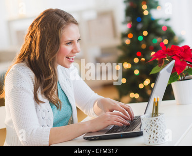 USA, New Jersey, Jersey City, Young woman working on laptop with Christmas tree on background Stock Photo