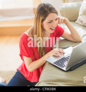 USA, New Jersey, Jersey City, Portrait of young woman working with laptop in living room Stock Photo