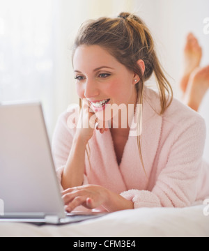 USA, New Jersey, Jersey City, Portrait of young woman with laptop in bedroom Stock Photo