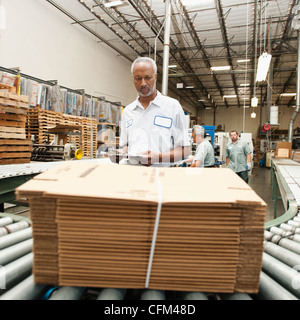 USA, California, Santa Ana, Worker inspecting bundle on conveyor belt Stock Photo