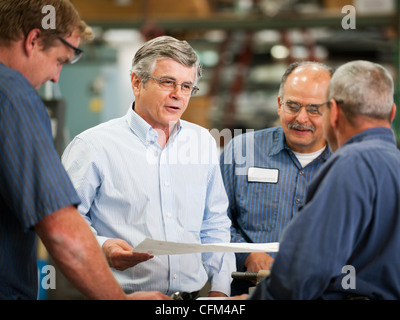 USA, California, Santa Ana, Businessman and workers talking in factory Stock Photo