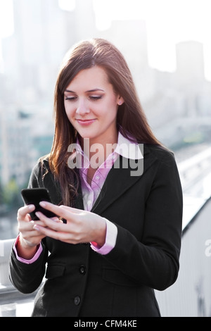 USA, Seattle, Smiling young businesswoman sending text message Stock Photo