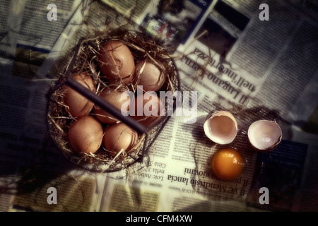 Eggs in a basket with straw on newsprint Stock Photo