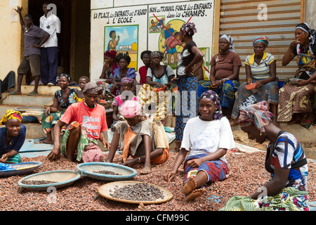 Women sorting  beans of cacao in front of a public notice against the child labor ,Duekoue, Ivory Coast ,Cote d'Ivoire Stock Photo