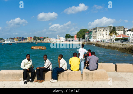 Young man sitting at the harbour front in Stone Town Zanzibar Tanzania Stock Photo
