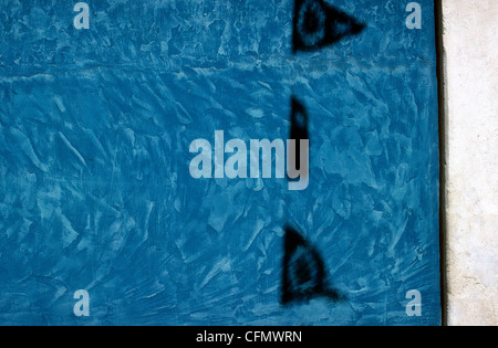 Shadow of flags on a blue coloured rough plastered wall. Stock Photo