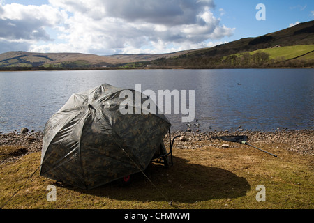 Coarse Fisherman under camouflage umbrella. Fishermen on Lake Semerwater, North Yorkshire Dales and National Park, Wensleydale, UK Stock Photo