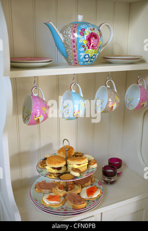 High tea. A selection of cakes and open sandwiches on a tiered cake stand. Stock Photo