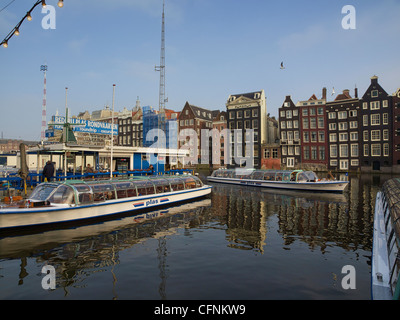 canal cruise boats in Amsterdam the Netherlands with a row of historic buildings in the background Stock Photo