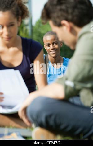 University students studying outdoors, focus on one man in background Stock Photo