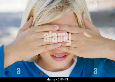 Boy covering eyes with hands Stock Photo