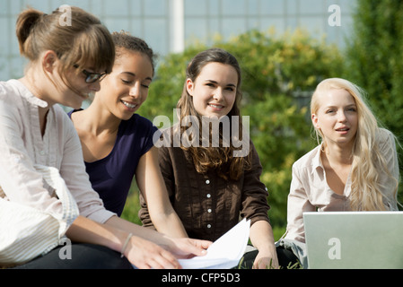 Female university students studying together outdoors, focus on two women Stock Photo