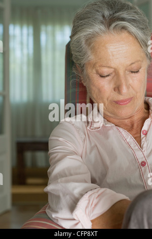 Senior woman napping in armchair Stock Photo