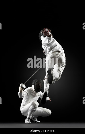 Fencers fencing, one fencer jumping in air Stock Photo