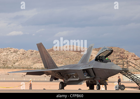 USAF F-22 Raptor air superiority fighter on ground with crew preparing for flight. Runway in desert. Stock Photo
