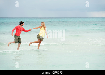 Couple running hand in hand in surf at the beach Stock Photo