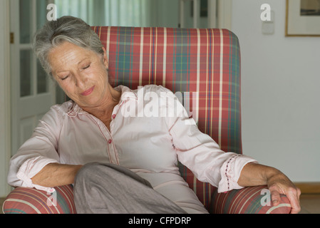 Senior woman napping in armchair Stock Photo