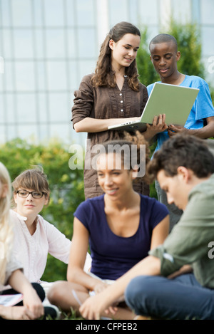 University students using laptop computer outdoors, focus on people in background Stock Photo