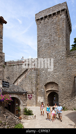 Family walking past entrance gateway to the Knights Templar fortified town the Cite de la Couvertoirade, Aveyron, France Stock Photo
