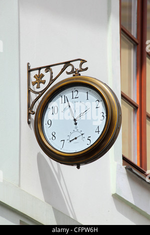 old round street watch hanging on a white wall Stock Photo