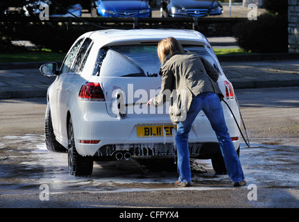 Female motorist using manual car wash. Morrisons Supermarket, Kendal, Cumbria, England, United Kingdom, Europe. Stock Photo