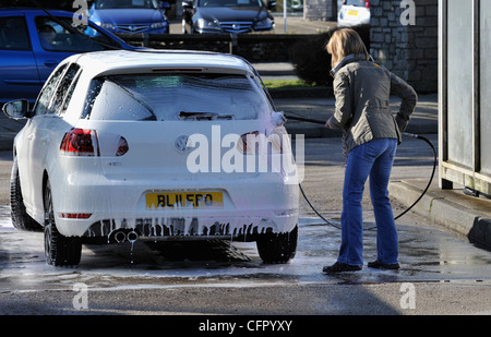 Female motorist using manual car wash. Morrisons Supermarket, Kendal, Cumbria, England, United Kingdom, Europe. Stock Photo