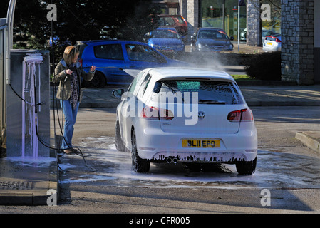 Female motorist using manual car wash. Morrisons Supermarket, Kendal, Cumbria, England, United Kingdom, Europe. Stock Photo