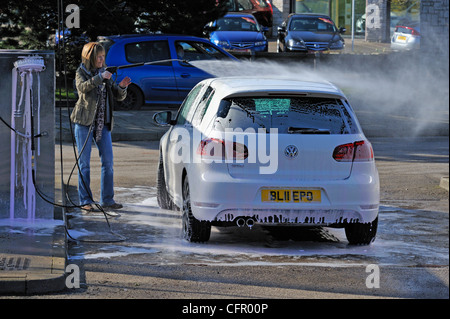 Female motorist using manual car wash. Morrisons Supermarket, Kendal, Cumbria, England, United Kingdom, Europe. Stock Photo