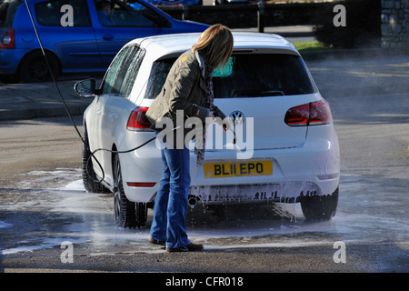 Female motorist using manual car wash. Morrisons Supermarket, Kendal, Cumbria, England, United Kingdom, Europe. Stock Photo