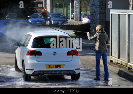 Female motorist using manual car wash. Morrisons Supermarket, Kendal, Cumbria, England, United Kingdom, Europe. Stock Photo