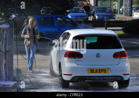 Female motorist using manual car wash. Morrisons Supermarket, Kendal, Cumbria, England, United Kingdom, Europe. Stock Photo