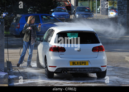 Female motorist using manual car wash. Morrisons Supermarket, Kendal, Cumbria, England, United Kingdom, Europe. Stock Photo