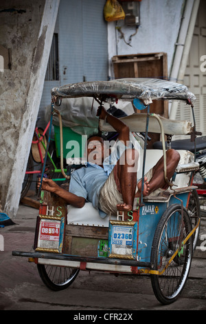 Driver sleeping in his taxi rickshaw (tricycle) in Makassar, Sulawesi, Java, Bali, South Pacific, Indonesia Southeast Asia. Stock Photo