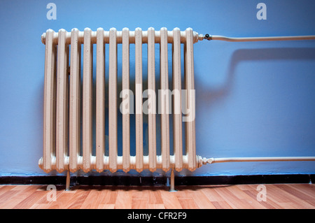 Heating radiator on purple wall in a room with laminated wooden floor Stock Photo