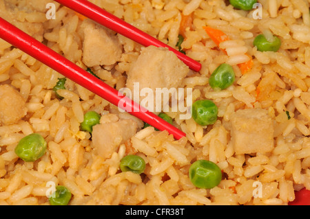 Close-up macro of chopsticks with chicken fried rice and vegetables Stock Photo