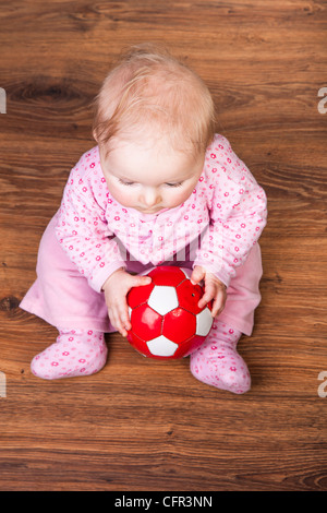 Infant child playing with bricks on wooden floor Stock Photo